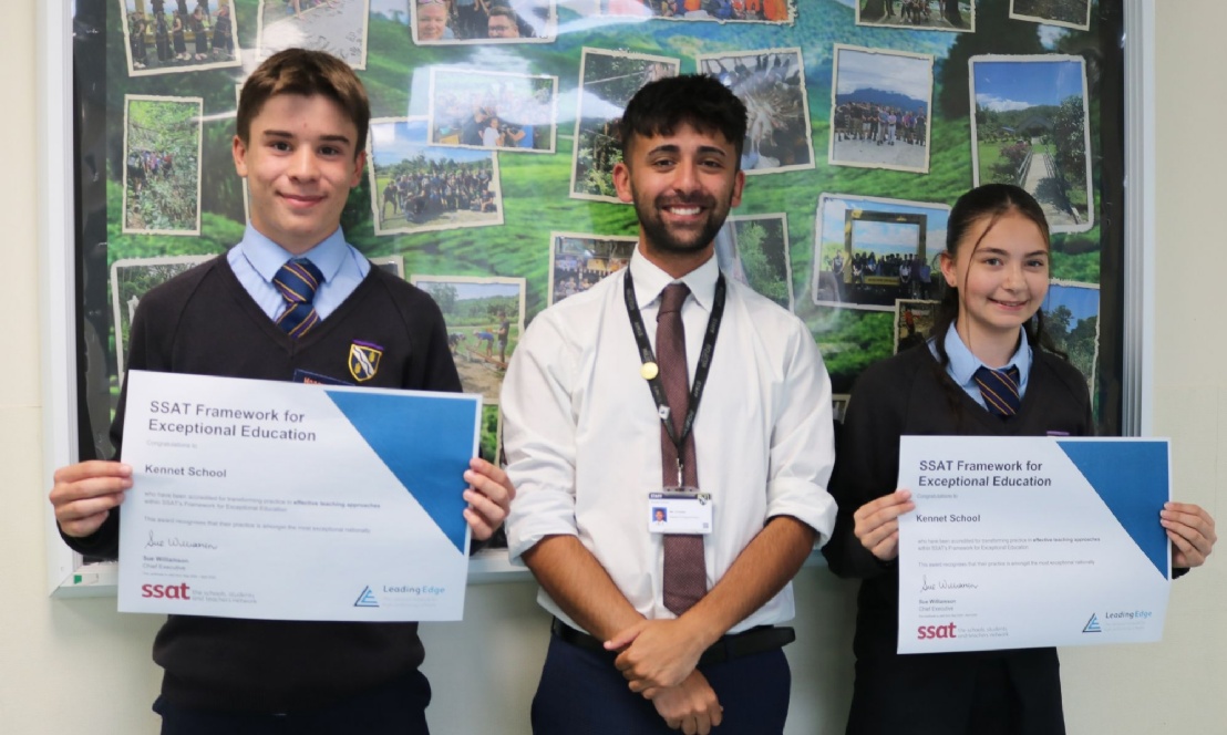 A teacher and a group of pupils smiling and proudly holding up the school's recent SSAT award.