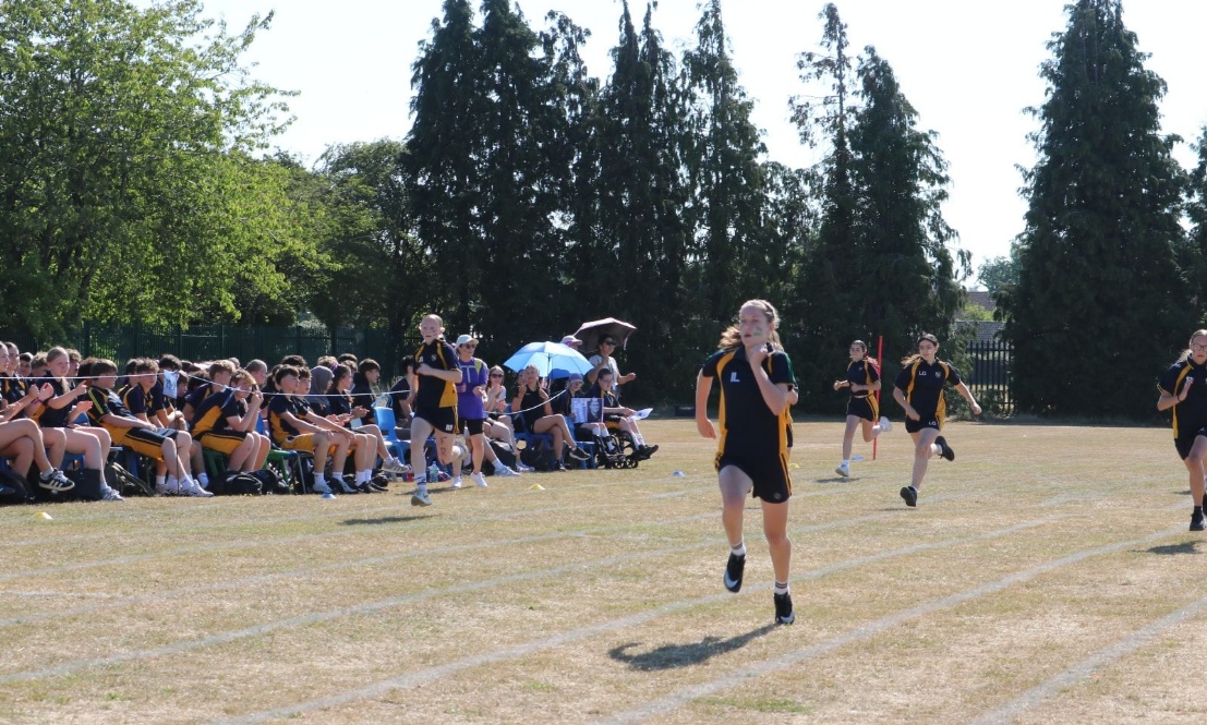 St Patrick pupil leading a track race with cheering spectators in the background.